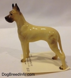 The left side of a figurine of a tan with black Great Dane. The figurine has a long body and it is glossy.