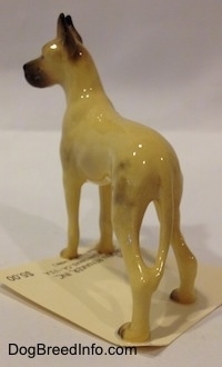 The back left side of a tan with black Great Dane figurine that has a long tail.