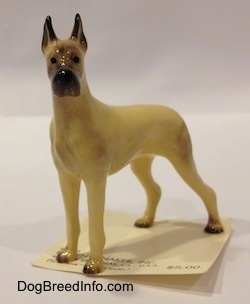 The front right side of a tan with black Great Dane figurine. The figurine has black circles for eyes.