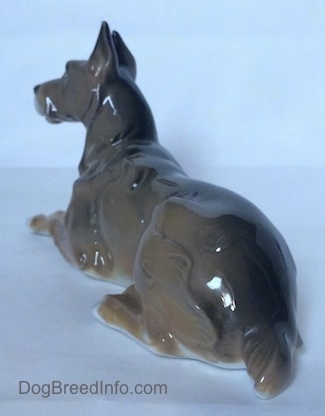 The back left side of a Great Dane laying down figurine. The figurine has a long body.