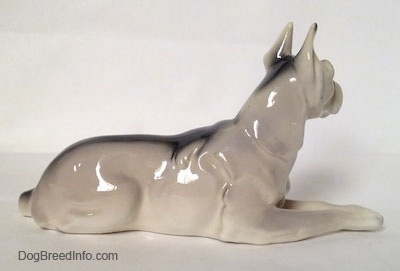 The right side of a white with black Great Dane laying down figurine. There is a black strip going across the body of the figurine.