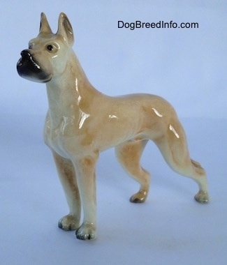 The front left side of a figurine of a tan Great Dane. The figurine has a black muzzle.