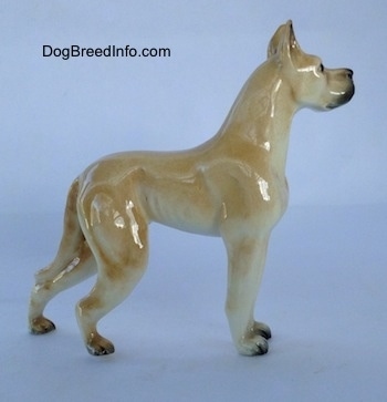 The right side of a figurine of a tan Great Dane. The figurine is glossy.