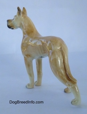 The back left side of a tan figurine of a Great Dane. The figurine has a long detailed body.