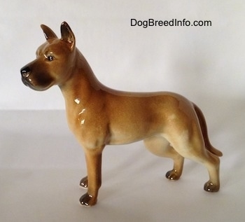 The left side of a brown with tan Great Dane figurine. The figurine has brown long legs and small black paws.