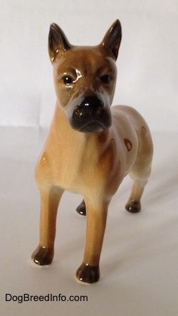 A tan Great Dane figurine in a standing pose. It has a detailed face and black circles for eyes.