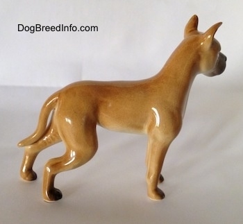 The right side of a figurine of a tan Great Dane. The figurine has a glossy body.