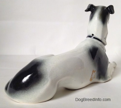 The back right side of a white with black and tan Greyhound. The figurine has a large black spot on above its tail.