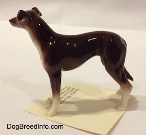 The left side of a brown with white Greyhound figurine. The figurine has a long slender body.