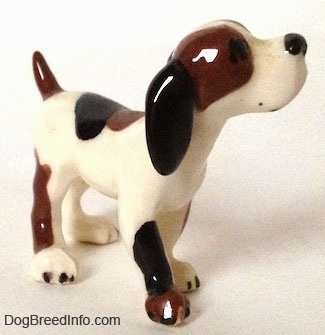 The front right side of a vintage Hound dog figurine. The figurine has a very glossy outside. The dog is looking upward.