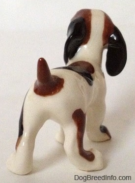 The back right side of a white with black and brown vintage Hound Dog figurine. The tail of the figurine is brown and short.