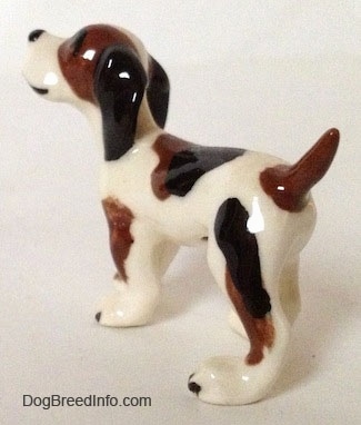 The back left side of a white with black and brown Hound dog figurine.