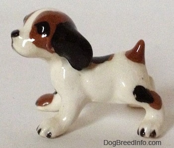 The left side of a white with brown and black vintage Hound Dog figurine. The figurine has big black circles for eyes.