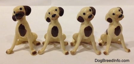Four miniature Hound Dog Mama figurines have brown spots on there chests and there heads are tilted to the left.