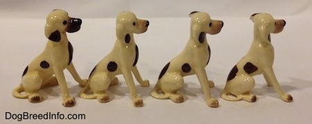 The right side of a four Miniature Hound Dog figutines. Each figurine has one brown spot on there sides and a brown spot at the bottom of the ears.