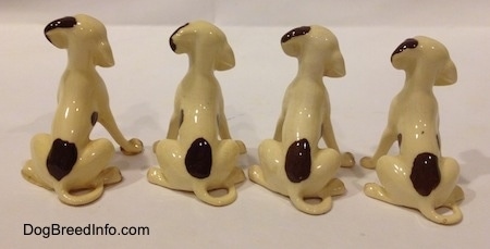 Four Miniature Hound Dog back facing figurines. The figurines have long thin tails and a brown spot towards there bottoms.