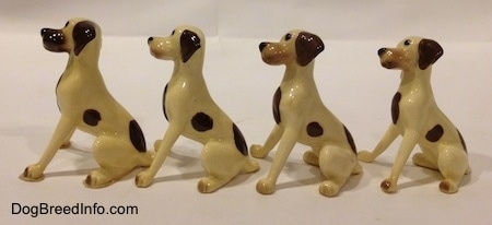 The left side of four white with brown spots Miniature Hound Dog Mama figurine. The figurines have completely brown left ears.