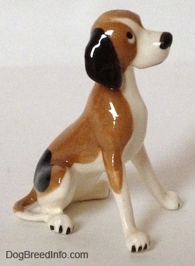The right side of a white and brown with black spots vintage Hound dog figurine. The figurine has long black ears attached to the side of its head.