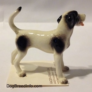 The right side of a figurine of dog standing. The figurine has a long curled up tail.