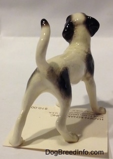 The back right side of a white with black dog figurine. The figurine has black ears.