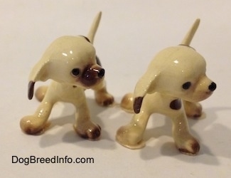 The front of two brown spotted Hound puppy figuirnes. Both figurines have glossy white heads and brown tipped ears.