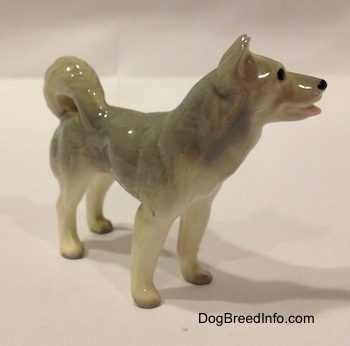 The front right side of a Husky figurine. The tail of the figurine has its tail arched onto its back.