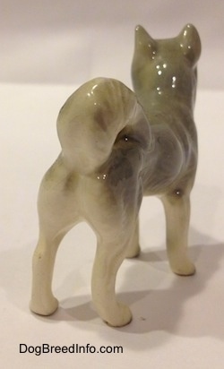 The back right side of a Husky figurine that is grey and white. The figurine has a long shapely body.