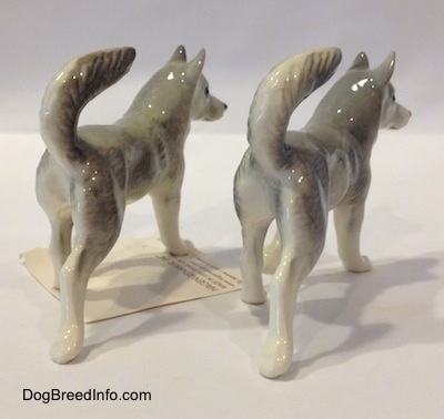 The back right side of two grey with white Husky figurines. The figurines have long glossy body