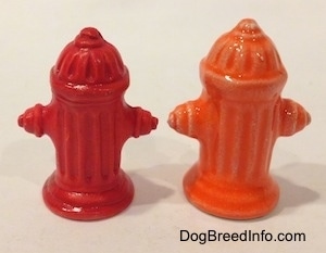 The back of two color variations of a fire hydrant. One hydrant is red and the other is orange.