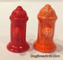 Two differnet color variations of a red fire hydrant and an orange fire hydrant. The valves of the hydrants are prominant.