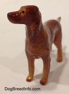 The front left side of an Irish Setter figurine. The figurine has black circles for eyes.
