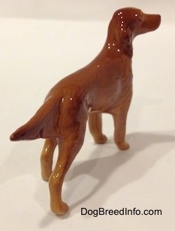 The back right side of a brown Irish Setter figurine. The figurine has long legs and small paws.