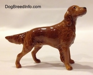 The right side of a brown Irish Setter figurine that is looking up. The tail of the figurine is lifted, but tilted towards the ground.