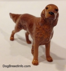 An Irish Setter figurine that has black circles for eyes and a black circle for a nose.
