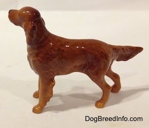 The left side of a figurine of an Irish Setter. The figurine is glossy and it has hair details on the back of its legs.