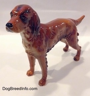 The front left side of a brown with black Irish Setter figurine. The figurine has black circles for eyes.