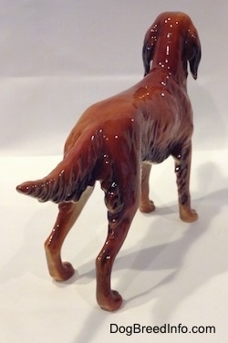 The back right side of a brown with black Irish Setter figurine. The figurine has a glossy back.