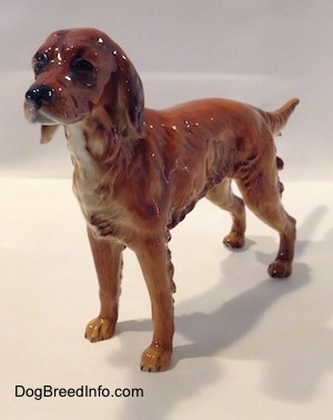 The front left side of a brown with black Irish Setter figurine. The figurine has a fine face details.