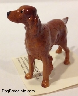 The back left side of a Irish Setter figurine. The figurine has its tail sticking out and it is level with its body.