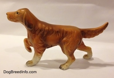 The right side of a ceramic brown Irish Setter figurine. The figurine has its tail up and extended out. It has hair draped at the bottom of its tail.