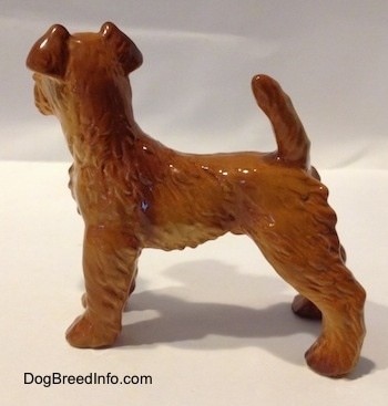 The left side of a figurine of a Golden red Irish Terrier. The figurine has its tail arched sticking in the air.