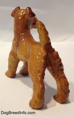 The back left side of an Irish Terrier dog figurine. The figurine has a ruffled hair on its back legs and its short tail is up in the air.