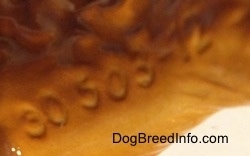 Close up - The underside of an Irish Terrier figurine. On the figurine it has the numbers - 30-503-12 - engraved on it.