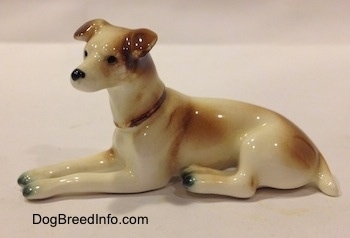 The left side of a brown and white Jack Russell Terrier figurine that is in a laying down pose. The figurine is wearing a red collar.