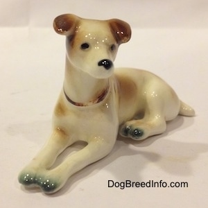 The front left side of a brown and white Jack Russell Terrier figurine. The figurine has a black circles for eyes.