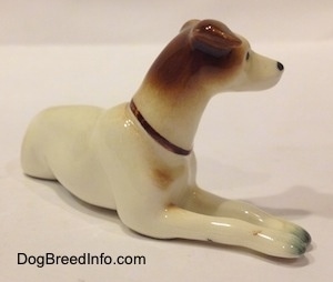 The front right side of a white and brown Jack Russell Terrier figurine. The figurine has long legs.