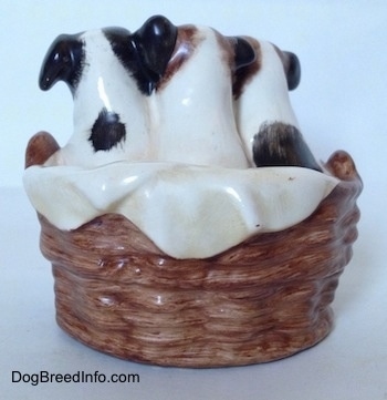The back of a figurine of three Jack Russell Terriers that are in a wicker basket. Two of the wicker baskets have spots on there backs.