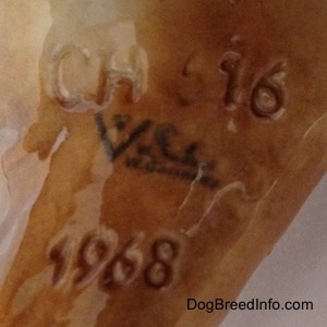 Close up - The underside of a brown Labrador Retriever figurine. The figurine has a Goebel mark of the bee inside of the V logo stamped on it and the numbers/letters combination of CH 616 is engraved at the bottom of the figurine.