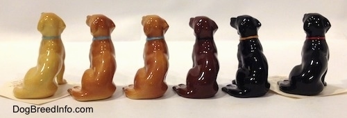 The back side of Labrador Retrievers figurines and their different color variations. The figurines tail are on the side of there legs.