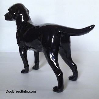 The back left side of a black Labrador Retriever figurine. The figurine has long legs.